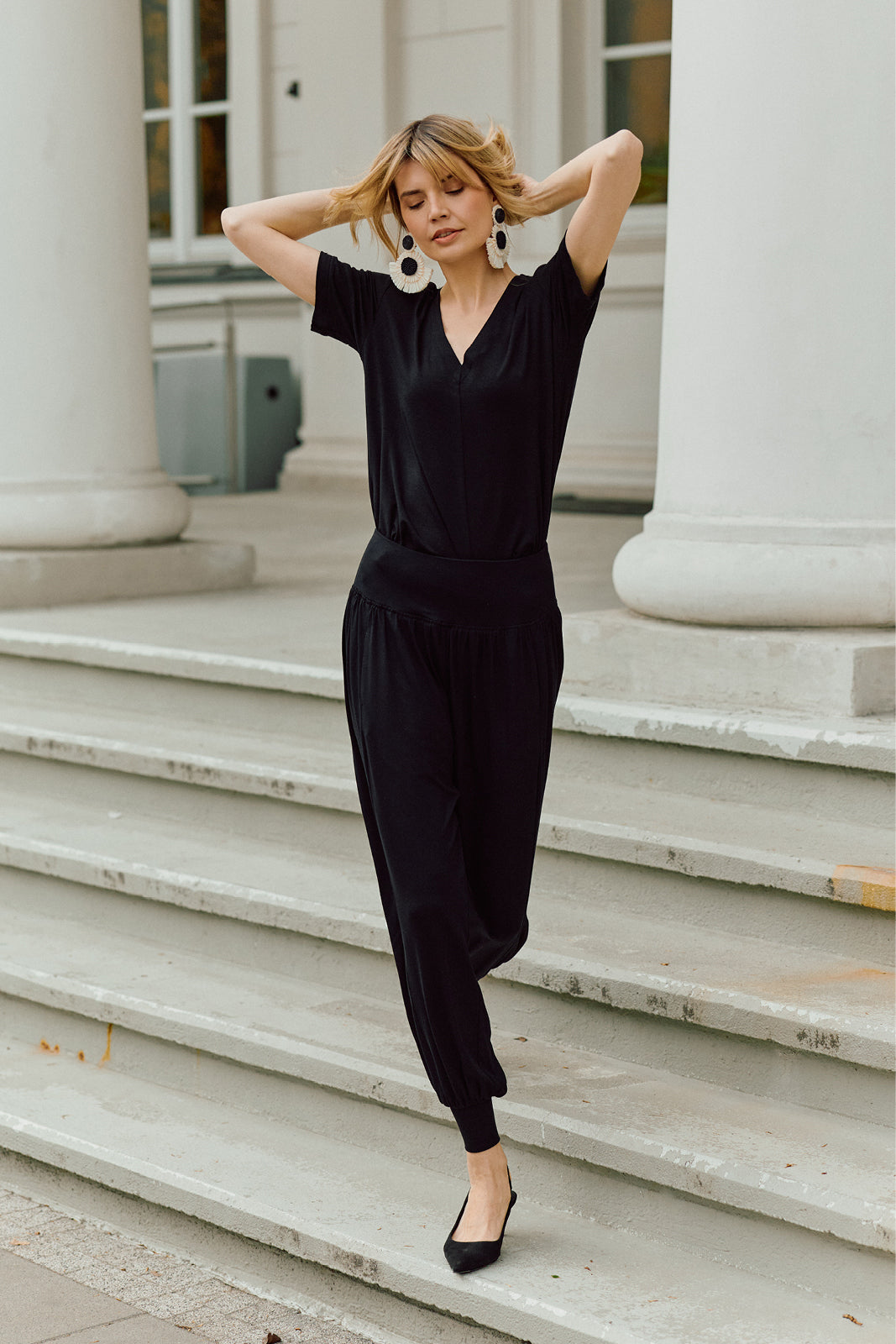 Czarny jumpsuit z dekoltem w kształcie litery V i elastyczną talią, idealny na co dzień, z eleganckimi kolczykami