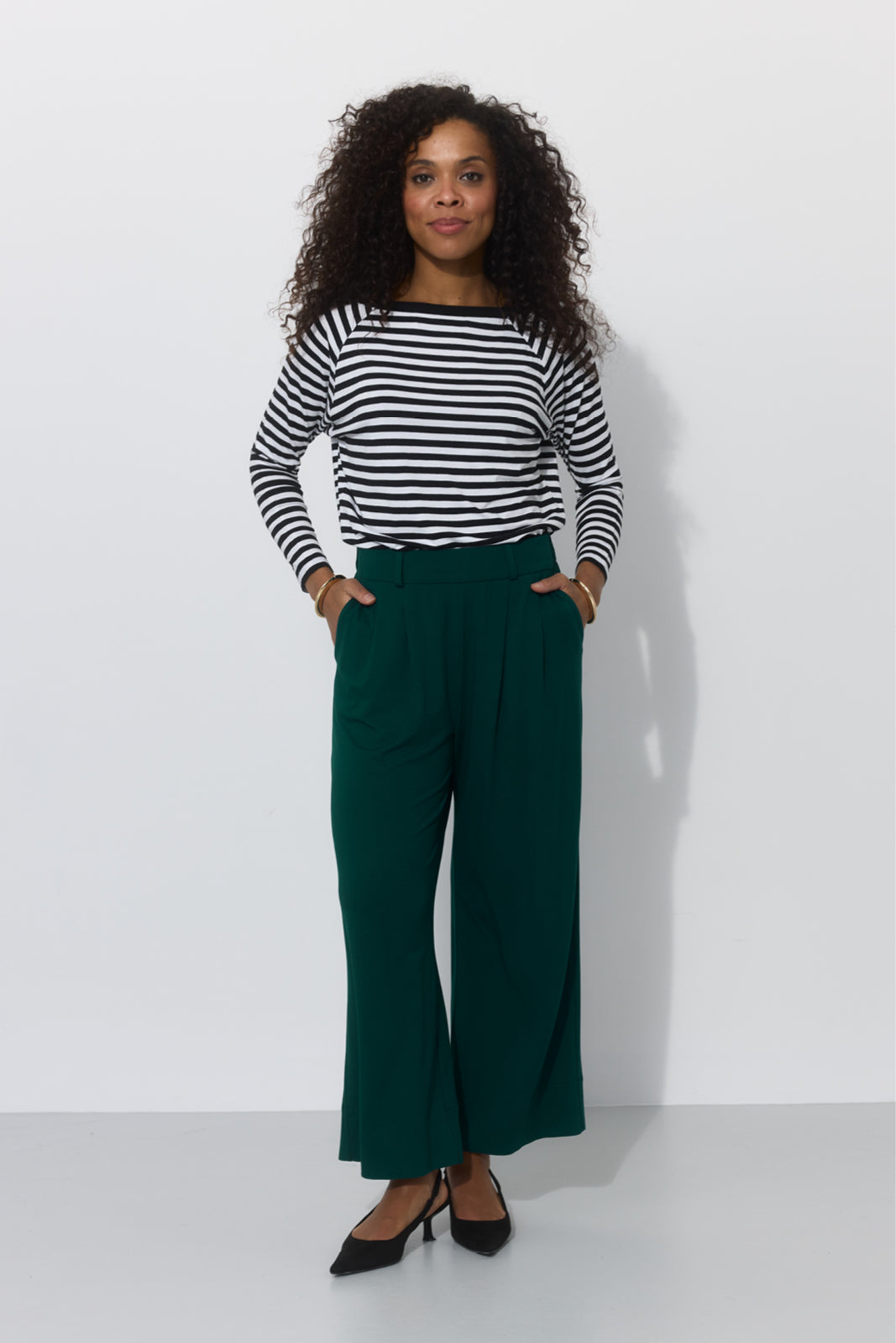 Kobieta w zielonych spodniach wide leg i koszulce w paski, stylowa i wygodna moda damska