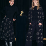 Dwie kobiety w eleganckich, czarnych strojach z delikatnym wzorem, stylowa moda polska z precyzyjnym krawiectwem
