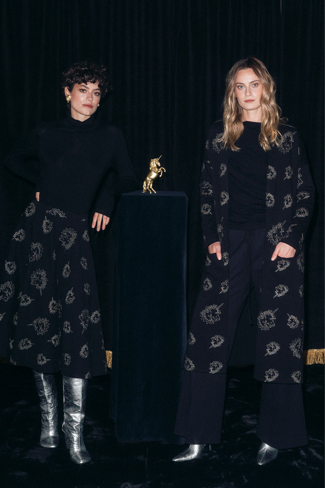 Dwie kobiety w eleganckich, czarnych strojach z delikatnym wzorem, stylowa moda polska z precyzyjnym krawiectwem
