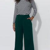 Kobieta w zielonych spodniach typu culottes i koszulce w paski, stylowy strój na co dzień