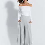 Szare spodnie dresowe typu wide leg z białą bluzką off-shoulder, stylowy i wygodny strój damska moda