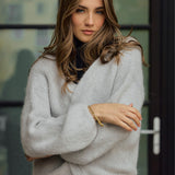 Delikatny, jasnoszary sweter z dzianiny, idealny na zimę, z elegancką złotą biżuterią